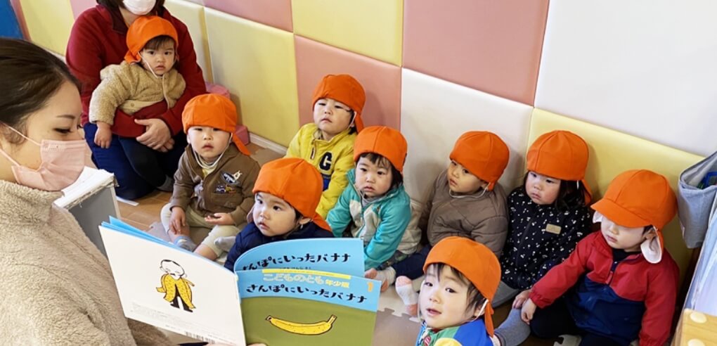 絵本を読み合いする園児と保育士